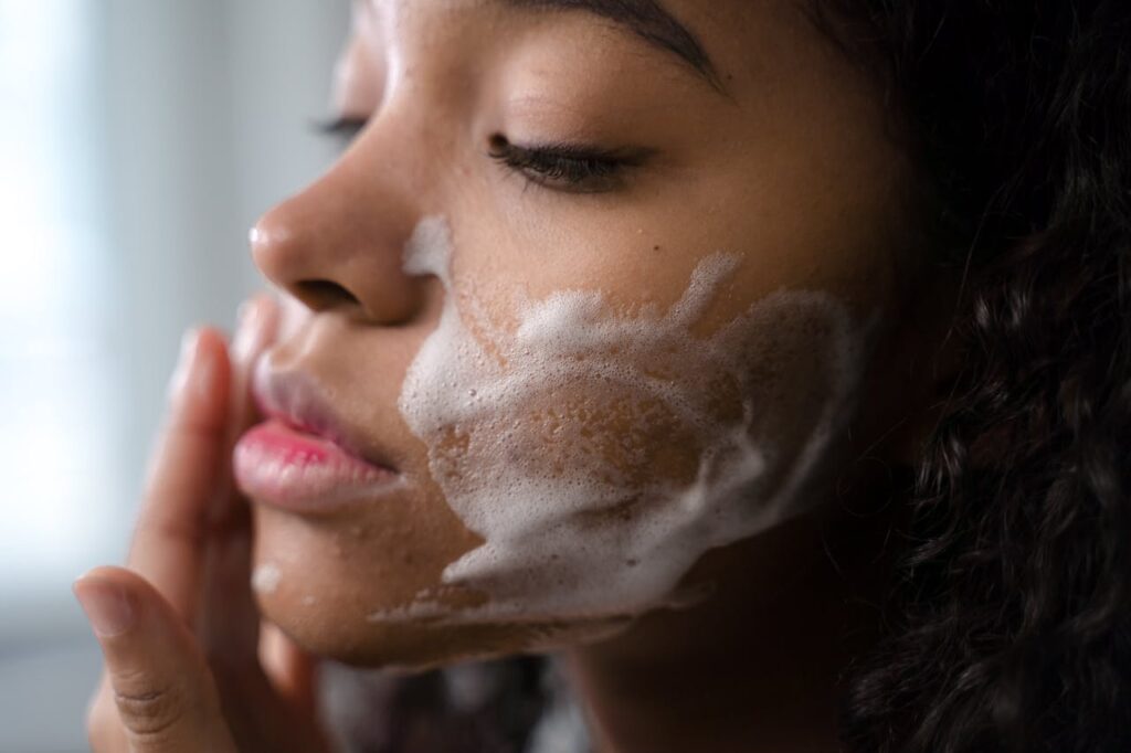 A woman applies skincare foam to her face for a gentle cleansing routine.